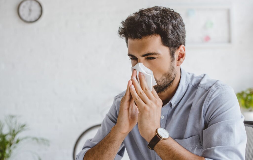 man blowing is noes from allergies